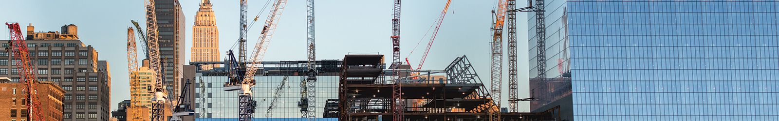 tall buildings under construction and cranes under a blue sky in New York City