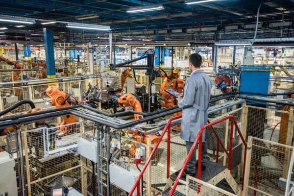 Engineer supervising automated machinery in a manufacturing facility